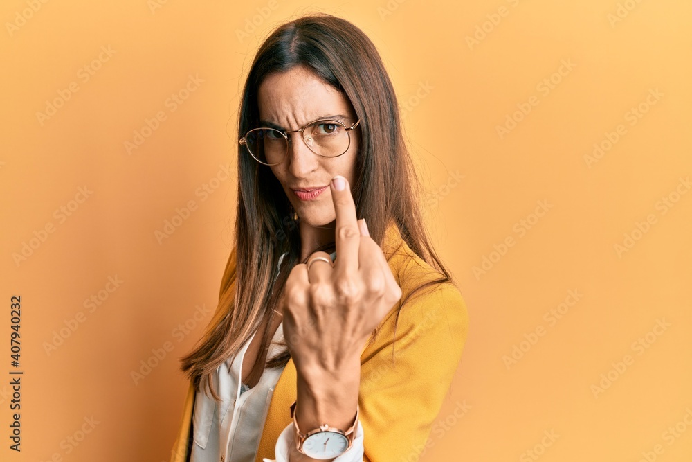 Young beautiful woman wearing business style and glasses showing middle finger, impolite and rude fuck off expression Young beautiful woman wearing business style and glasses showing middle finger, impolite and rude fuck off expression