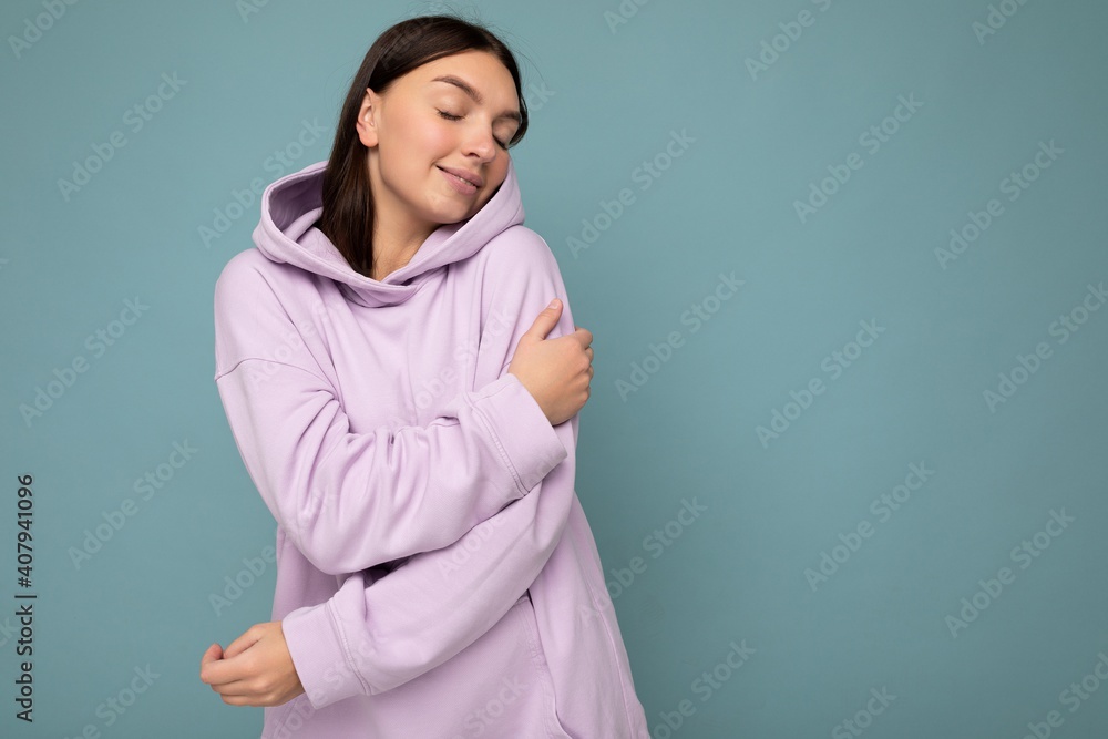 Cute happy young beautiful brunette woman with sincere emotions isolated on background wall with copy space wearing casual stylish purple hoodie. Positive concept Cute happy young beautiful brunette woman with sincere emotions isolated on background wall with copy space wearing casual stylish purple hoodie. Positive concept