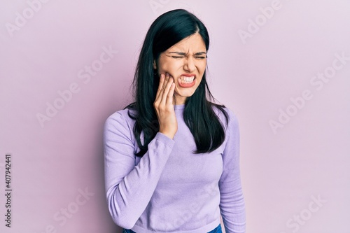 Young hispanic woman wearing casual clothes touching mouth with hand with painful expression because of toothache or dental illness on teeth. dentist
