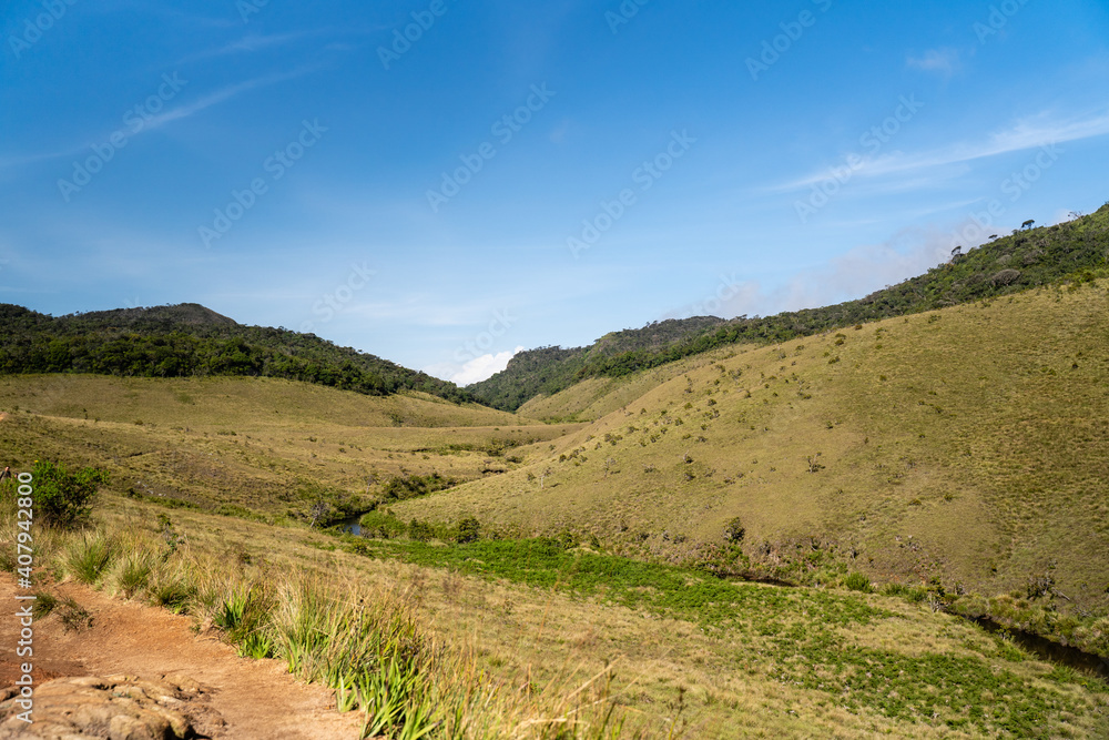 Blick auf grüne Wiesen und einen kleinen Bach im Horton Plains National Park im Hochland von Sri Lanka bei sonnigem Wetter Blick auf grüne Wiesen und einen kleinen Bach im Horton Plains National Park im Hochland von Sri Lanka bei sonnigem Wetter