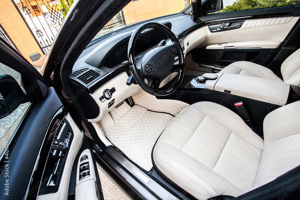 The car is inside. The interior of a prestigious modern car. Front seats with steering wheel, dashboard and display. beige leather interior with black dashboard.