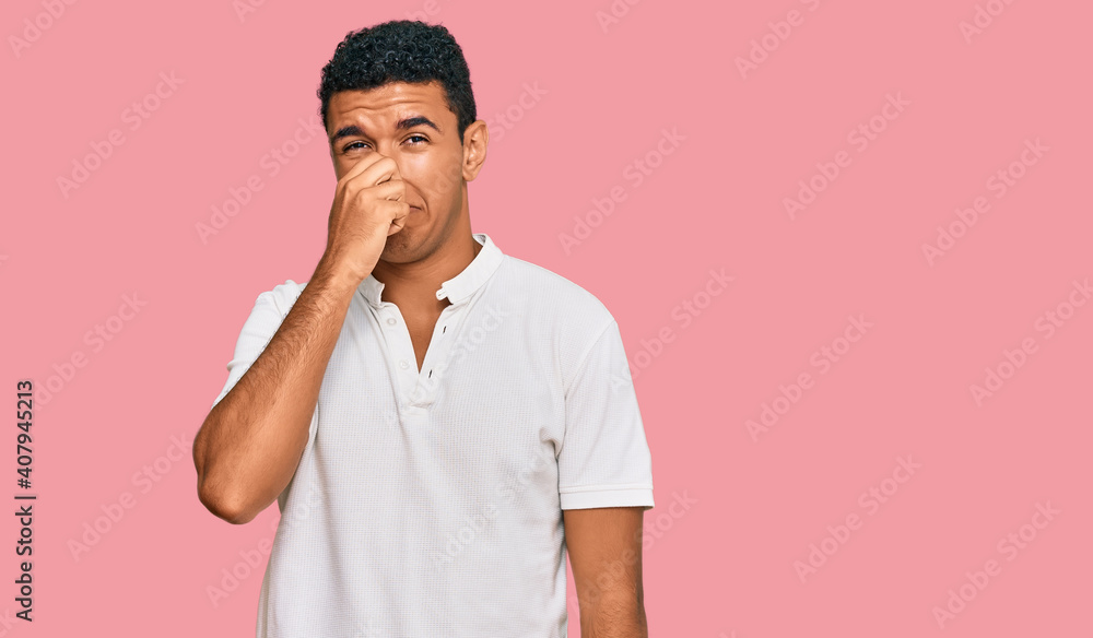 Young arab man wearing casual clothes smelling something stinky and disgusting, intolerable