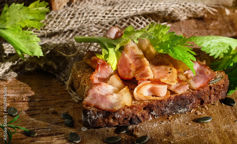 Sandwich with bacon and celery leaves on a slice of rye bread made from leaven with pumpkin seeds. Healthy food concept, traditional craft bread, close-up Sandwich with bacon and celery leaves on a slice of rye bread made from leaven with pumpkin seeds. Healthy food concept, traditional craft bread, close-up
