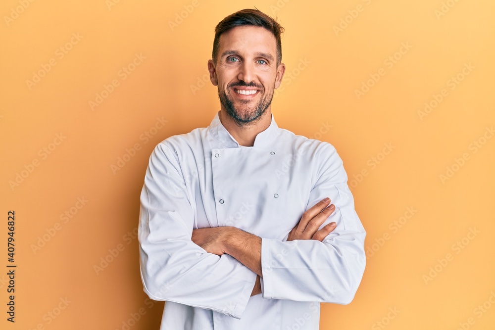 Handsome man with beard wearing professional cook uniform happy face smiling with crossed arms looking at the camera. positive person. Handsome man with beard wearing professional cook uniform happy face smiling with crossed arms looking at the camera. positive person.