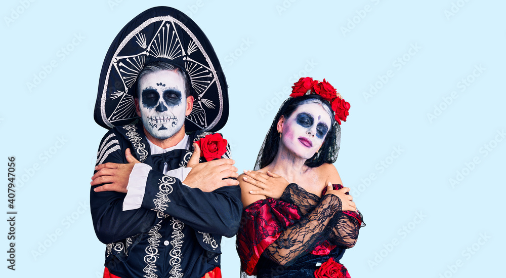 Young couple wearing mexican day of the dead costume over background hugging oneself happy and positive, smiling confident. self love and self care Young couple wearing mexican day of the dead costume over background hugging oneself happy and positive, smiling confident. self love and self care