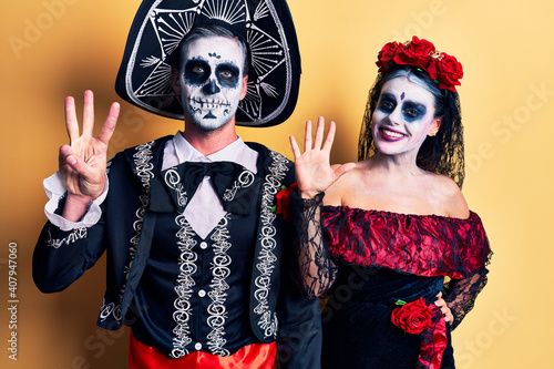 Young couple wearing mexican day of the dead costume over yellow showing and pointing up with fingers number eight while smiling confident and happy.