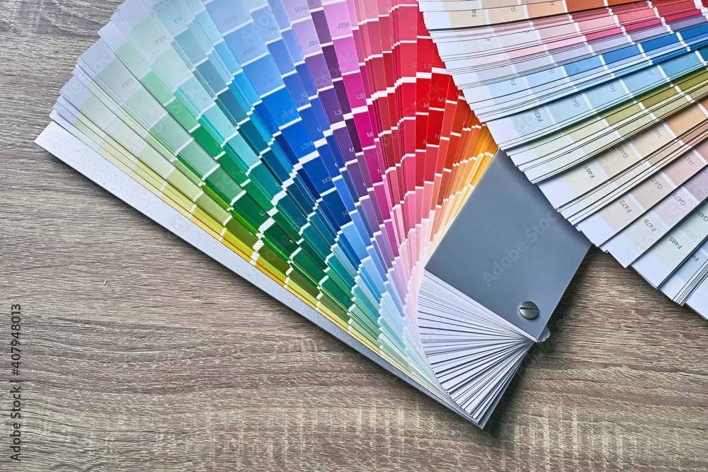 Color wheel palette for choosing paint tone. Various colors on wooden table background with copy space. Interior designer tool.