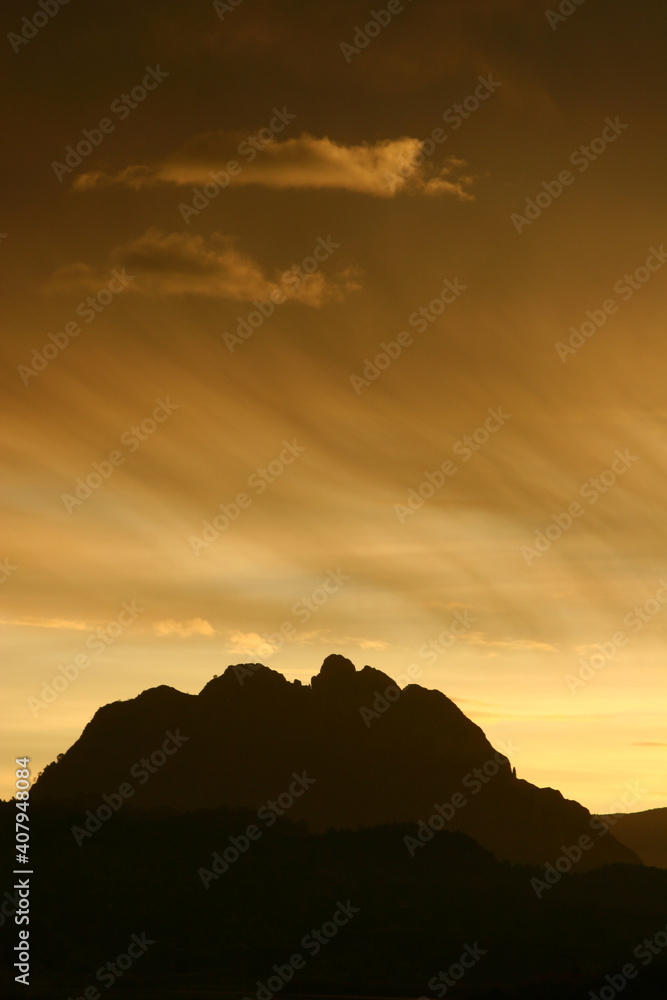 Montaña a contraluz al amanecer y cielo con nubes altas. Pico de El Almorchón, Cieza (Murcia-España).