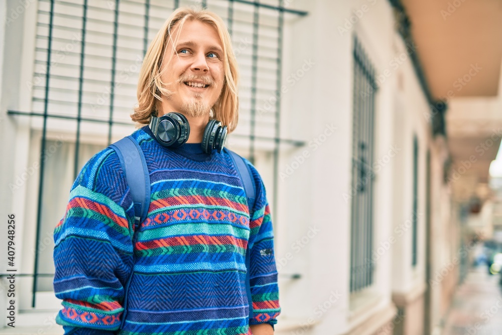 Young scandinavian student man smiling happy using headphones at the city. Young scandinavian student man smiling happy using headphones at the city.