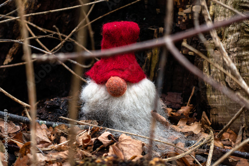 Gnome with red cap sitting amongst leaves and sticks