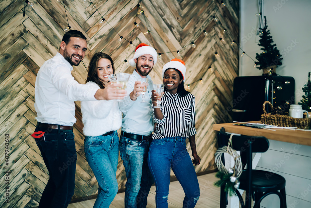 Happy multiethnic adult friends clinking glasses at Christmas party