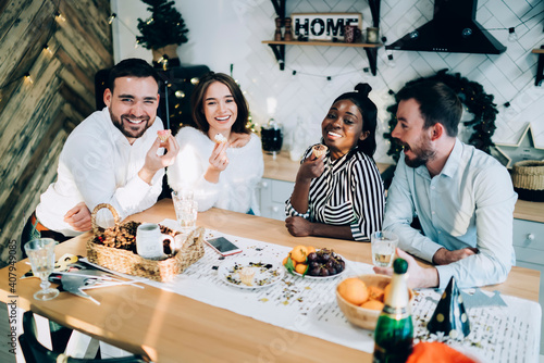 Cheerful group of friends having holiday dinner in kitchen