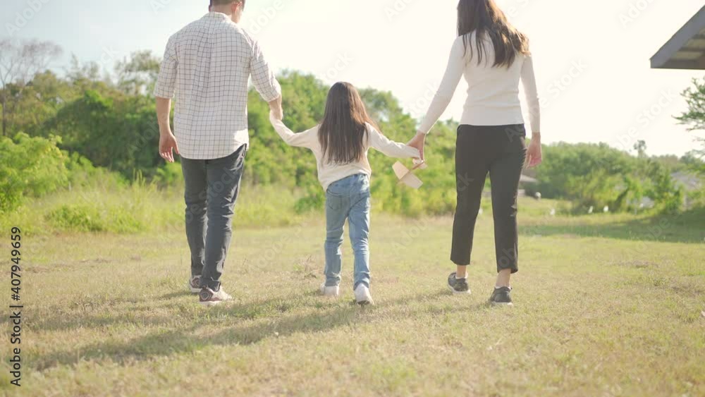 Happy young asian family walking on path holding hands his little girl, They are walk in the park and have enjoyed ourselves together in the green garden. Family enjoying sunny fall day in nature. Happy young asian family walking on path holding hands his little girl, They are walk in the park and have enjoyed ourselves together in the green garden. Family enjoying sunny fall day in nature.