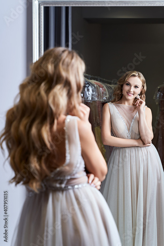 Принти на полотні Young beautiful blonde girl wearing a full-length silver white chiffon prom ball gown decorated with sparkles and sequins