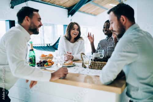 Happy friends talking on kitchen table