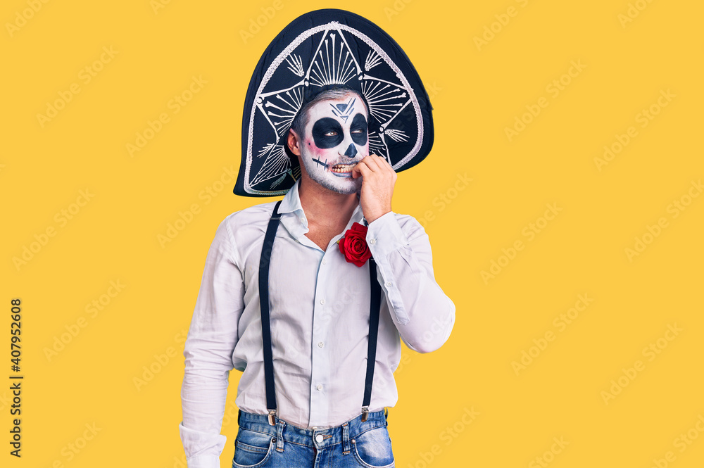 Man wearing day of the dead costume over background looking stressed and nervous with hands on mouth biting nails. anxiety problem. Man wearing day of the dead costume over background looking stressed and nervous with hands on mouth biting nails. anxiety problem.