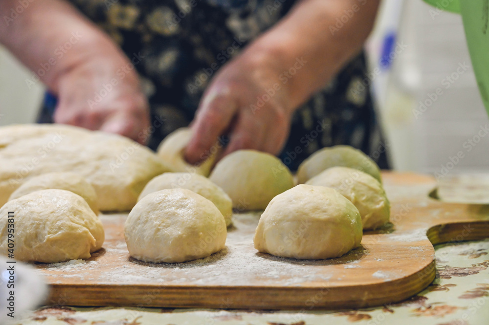 Baker makes dough and rolls dough balls on wooden board. Preparation for cooking pastries. Baker makes dough and rolls dough balls on wooden board. Preparation for cooking pastries.