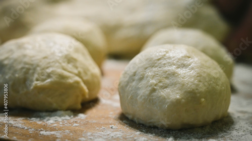 Raw dough balls and flour on wooden counter. Preparation for cooking pastries.
