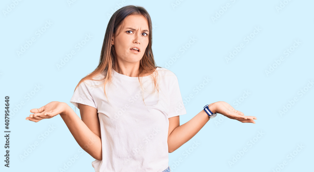Beautiful caucasian woman wearing casual white tshirt clueless and confused with open arms, no idea concept. Beautiful caucasian woman wearing casual white tshirt clueless and confused with open arms, no idea concept.