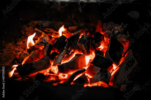 Red hot coals in the grill close up. Burning log of wood as abstract background.
