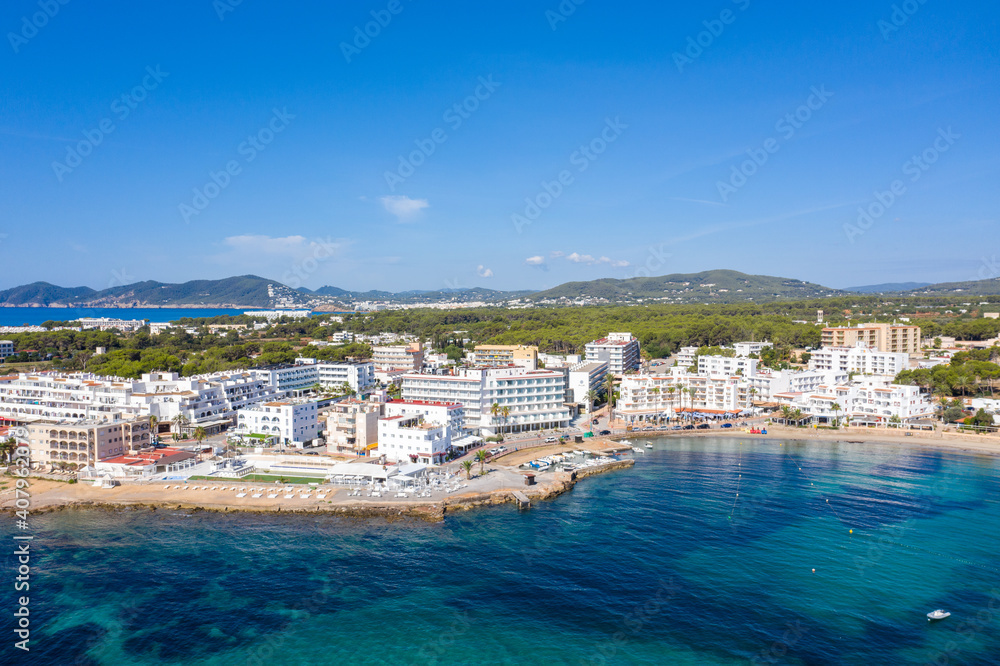 Aerial drone photo of the beautiful island of Ibiza in Spain showing the costal front golden sandy beaches with people relaxing and sunbathing on a hot sunny summers day