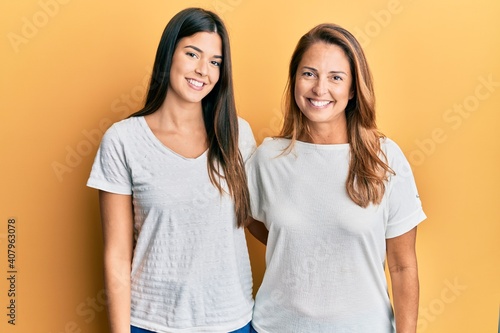 Hispanic family of mother and daughter wearing casual white tshirt with a happy and cool smile on face. lucky person.