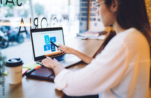 Cropped image on caucasian female student in casual wear using laptop computer for learning online course, rear view of businesswoman checking graphic chart of trade on web page on remote job