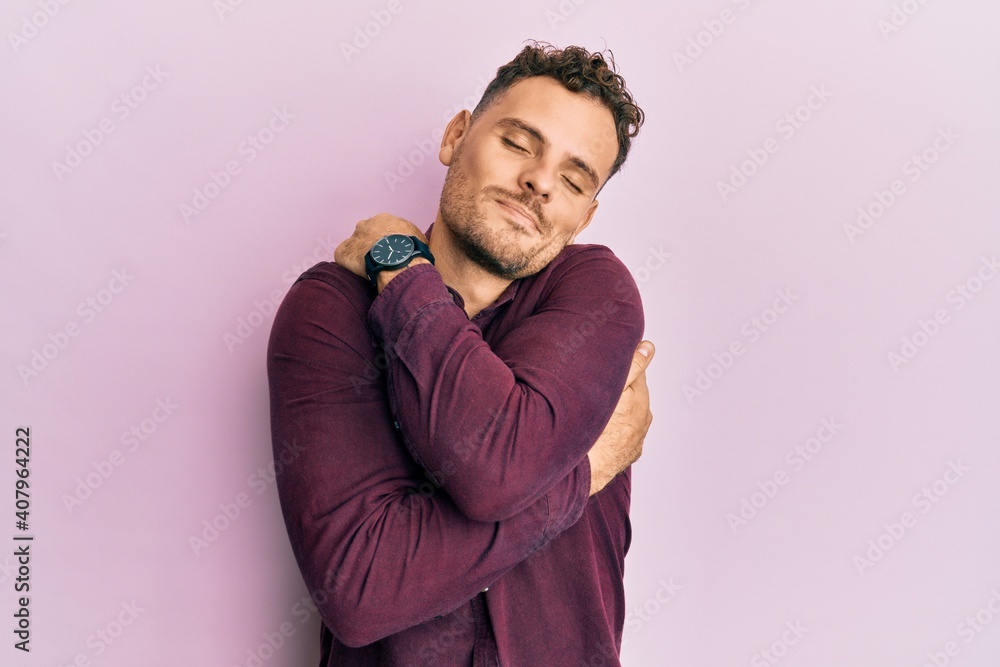 Young hispanic man wearing casual clothes hugging oneself happy and positive, smiling confident. self love and self care Young hispanic man wearing casual clothes hugging oneself happy and positive, smiling confident. self love and self care