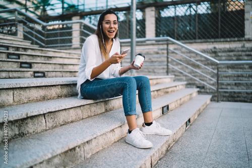 Smiling woman using phone while sitting on outdoor stairs
