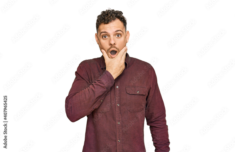 Young hispanic man wearing casual clothes looking fascinated with disbelief, surprise and amazed expression with hands on chin Young hispanic man wearing casual clothes looking fascinated with disbelief, surprise and amazed expression with hands on chin