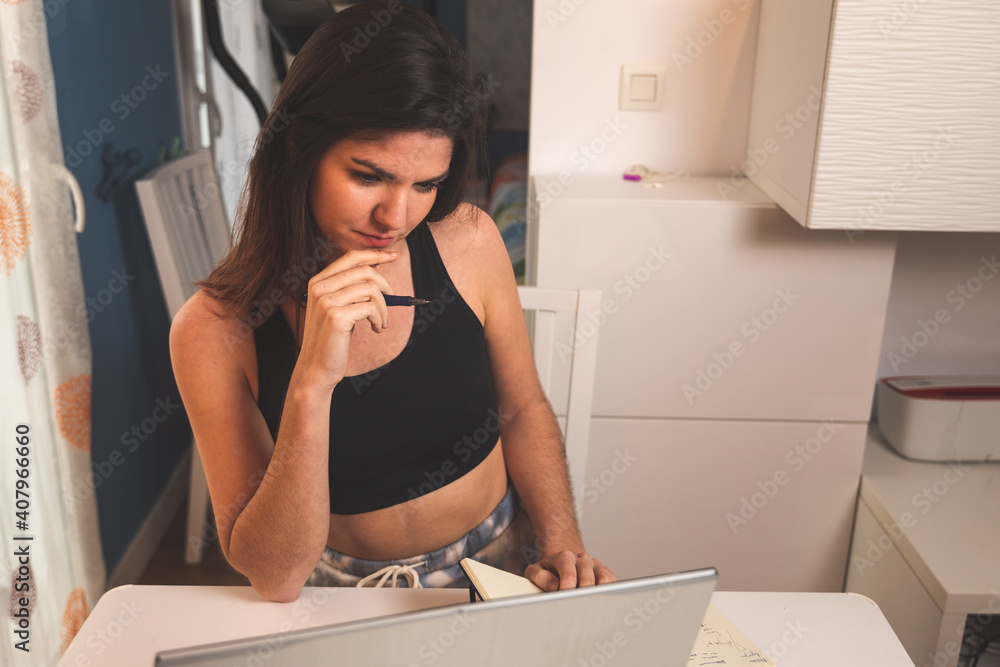 Young woman working with a laptop at home wearing sports clothes Young woman working with a laptop at home wearing sports clothes