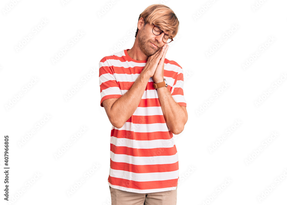 Handsome caucasian man with beard wearing casual clothes and glasses sleeping tired dreaming and posing with hands together while smiling with closed eyes. Handsome caucasian man with beard wearing casual clothes and glasses sleeping tired dreaming and posing with hands together while smiling with closed eyes.