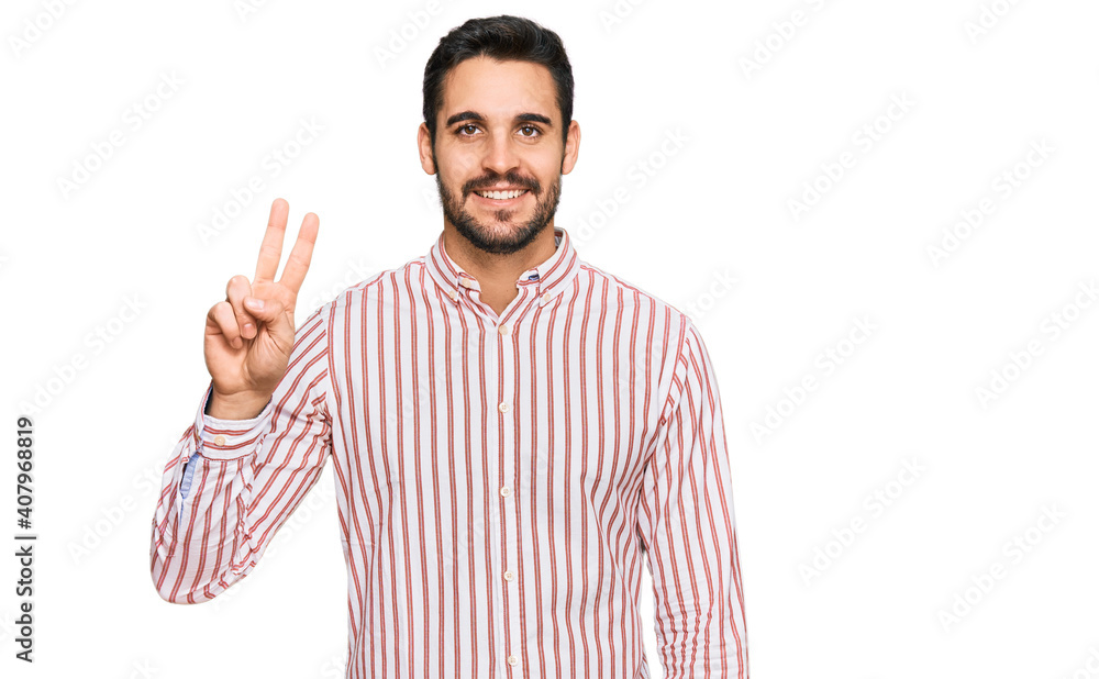 Young hispanic man wearing business shirt smiling with happy face winking at the camera doing victory sign. number two. Young hispanic man wearing business shirt smiling with happy face winking at the camera doing victory sign. number two.