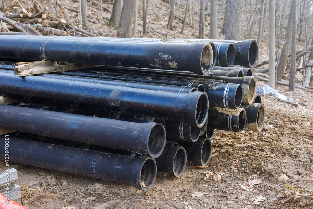 Plastic main black pipes on heap of polyethylene pipes for a water supply system for laying of city communications Plastic main black pipes on heap of polyethylene pipes for a water supply system for laying of city communications