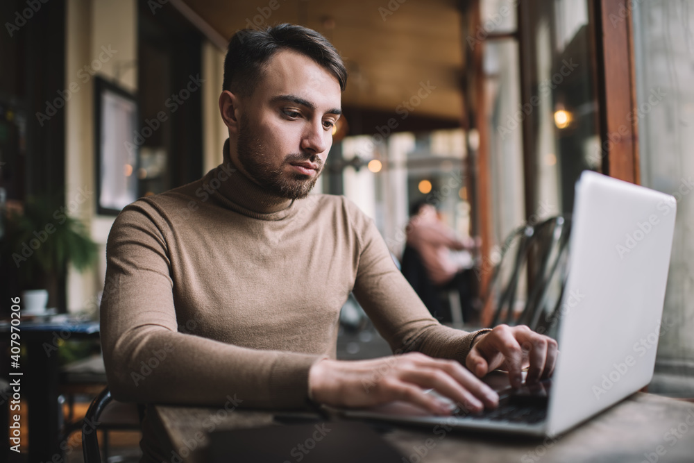 Serious man typing on laptop in cafe Serious man typing on laptop in cafe