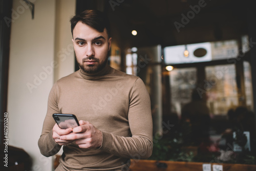 Calm man surfing smartphone in cafeteria