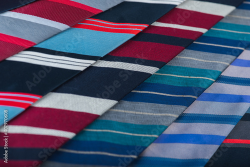 close-up view, many colorful folded ties, sloping horizon. Textured background of classic fabrics