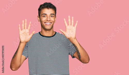 Young handsome african american man wearing casual clothes showing and pointing up with fingers number ten while smiling confident and happy.