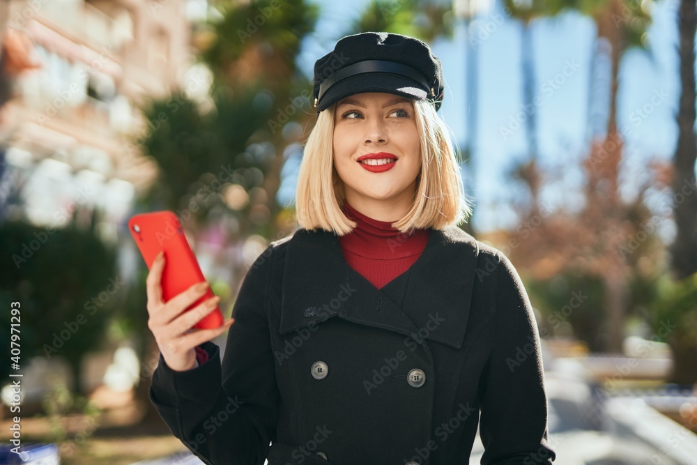 Young blonde woman smiling happy using smartphone at the park