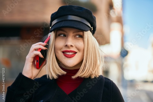 Young blonde woman smiling happy talking on the smartphone at the city.