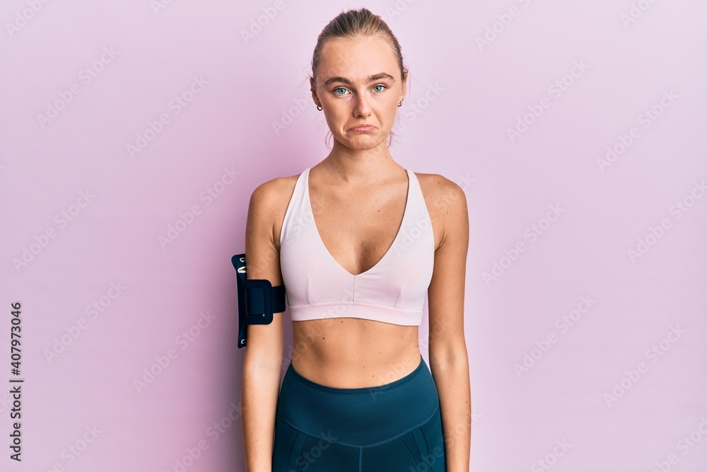 Beautiful blonde woman wearing sportswear and arm band depressed and worry for distress, crying angry and afraid. sad expression.