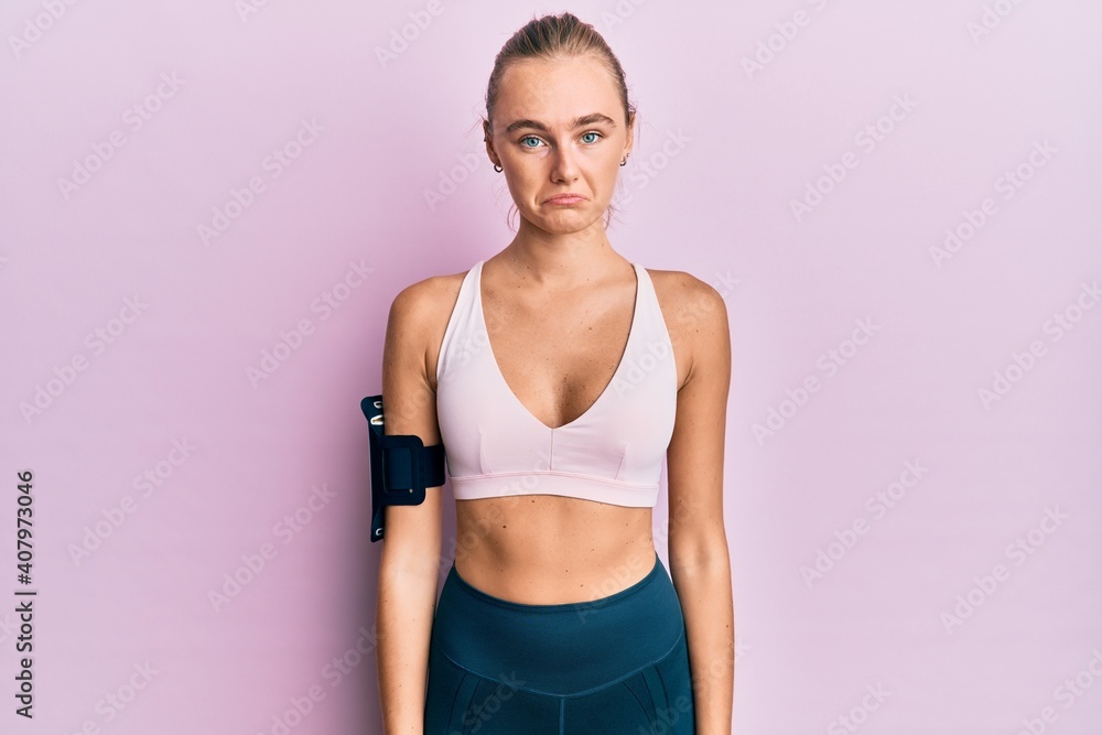 Beautiful blonde woman wearing sportswear and arm band depressed and worry for distress, crying angry and afraid. sad expression. Beautiful blonde woman wearing sportswear and arm band depressed and worry for distress, crying angry and afraid. sad expression.