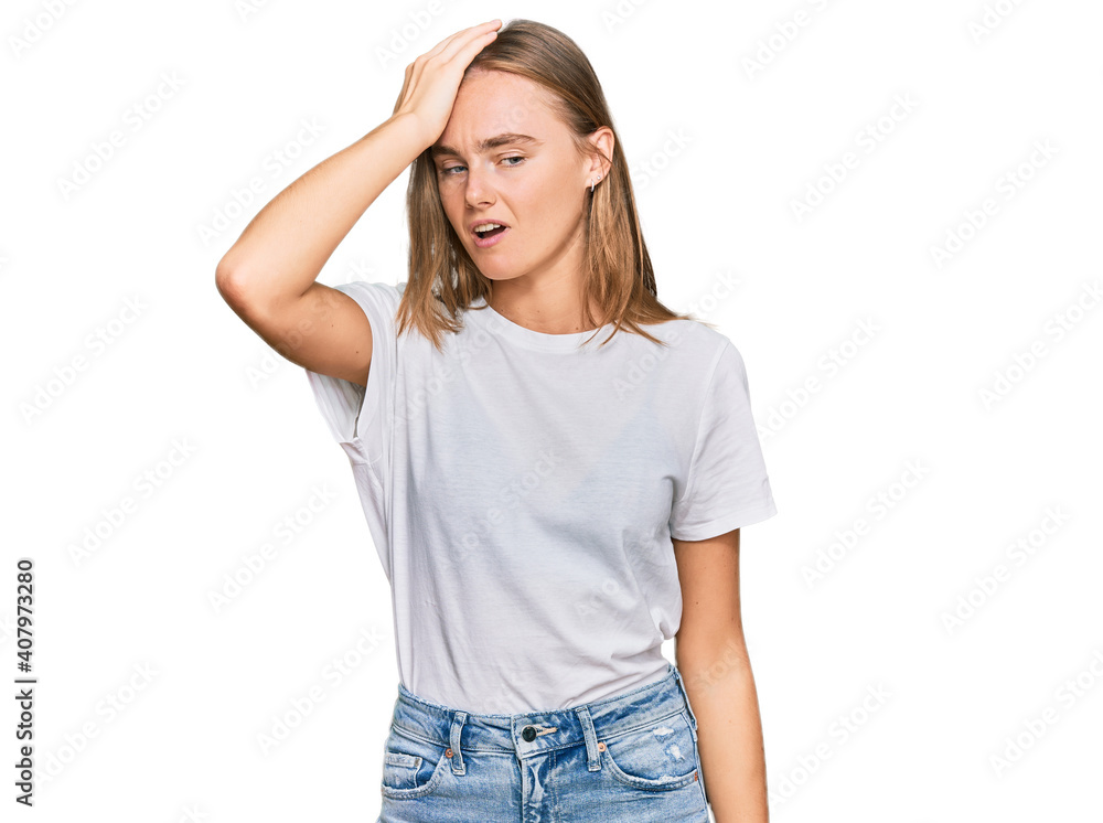 Obraz premium Beautiful young blonde woman wearing casual white t shirt surprised with hand on head for mistake, remember error. forgot, bad memory concept.