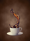 Coffee cup with splash of coffee isolated on blurred background