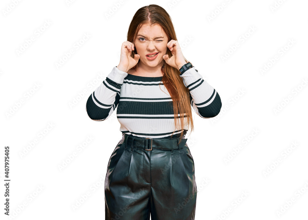 Young beautiful redhead woman wearing elegant clothes covering ears with fingers with annoyed expression for the noise of loud music. deaf concept. Young beautiful redhead woman wearing elegant clothes covering ears with fingers with annoyed expression for the noise of loud music. deaf concept.