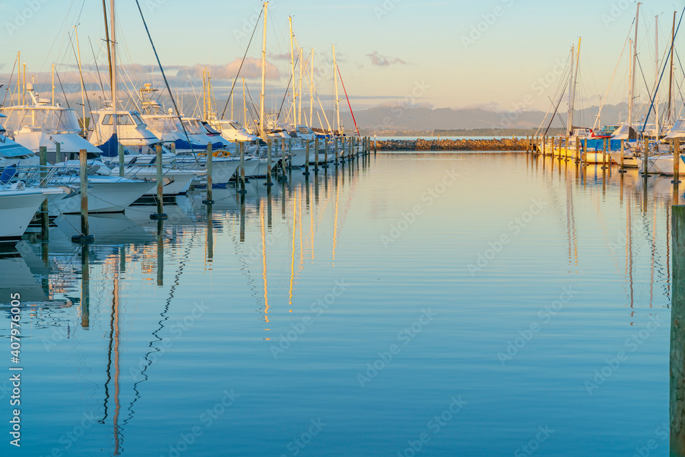 Tauranga Marina boats and piers reflected in calm water at sunrise