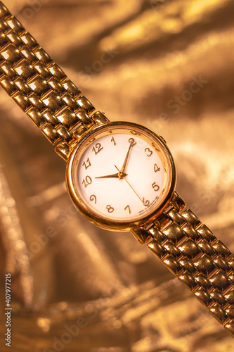 Foto Picture of a gold luxury watch in a gold background.