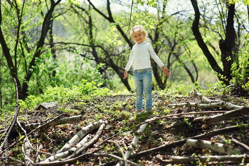 Little child girl playing in the spring forest.
