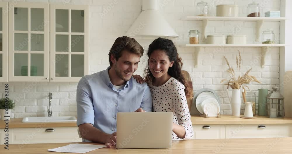 Bonding millennial smiling couple looking at laptop screen, choosing goods in online store involved in internet shopping, discussing planning vacation trip booking hotel or flight tickets on computer. Bonding millennial smiling couple looking at laptop screen, choosing goods in online store involved in internet shopping, discussing planning vacation trip booking hotel or flight tickets on computer.