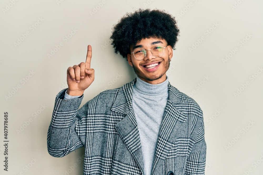 Young african american man with afro hair wearing casual clothes glasses smiling with an idea or question pointing finger up with happy face, number one Young african american man with afro hair wearing casual clothes glasses smiling with an idea or question pointing finger up with happy face, number one